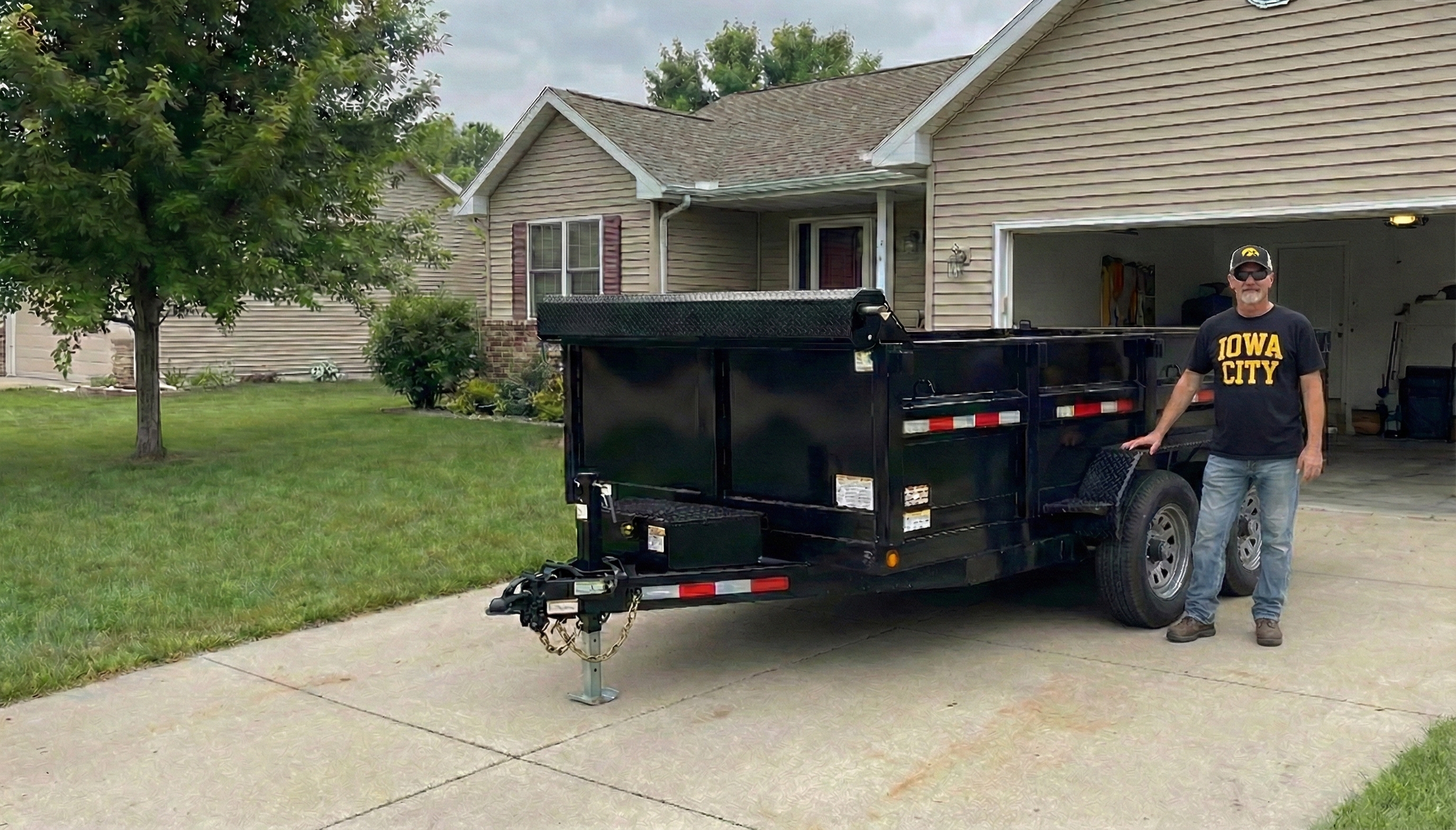 Terry standing next to his dump trailer in a residential driveway